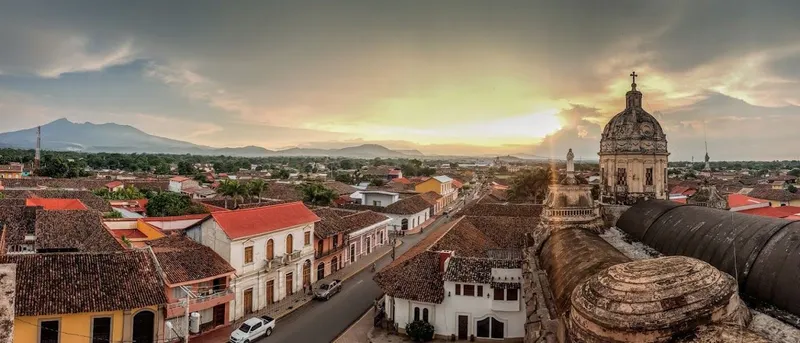 Panorama over de daken van Granada in Nicaragua, met de koepel van een kerk en bergen aan de horizon