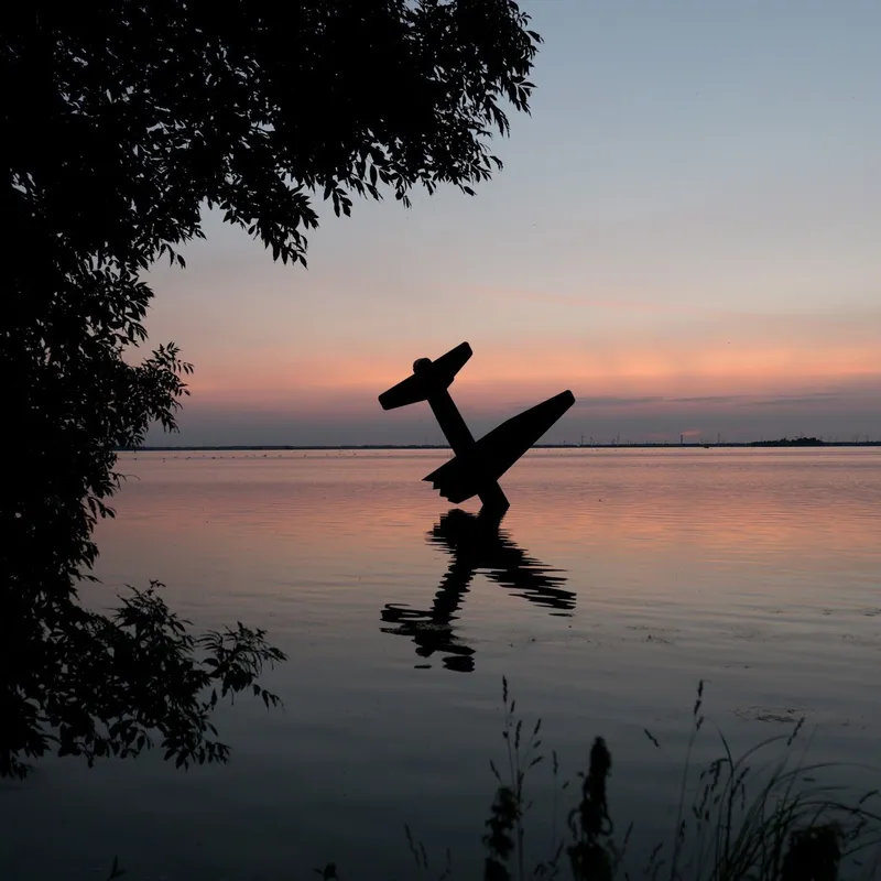 Silhouet van een vliegtuigbeeld in het water bij zonsondergang