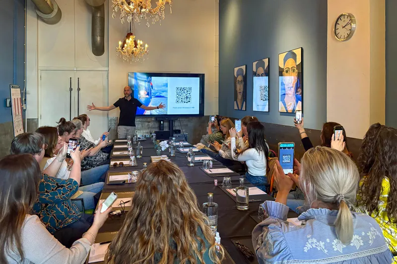 Een volle zaal met deelnemers die fotograferen terwijl Maarten presenteert