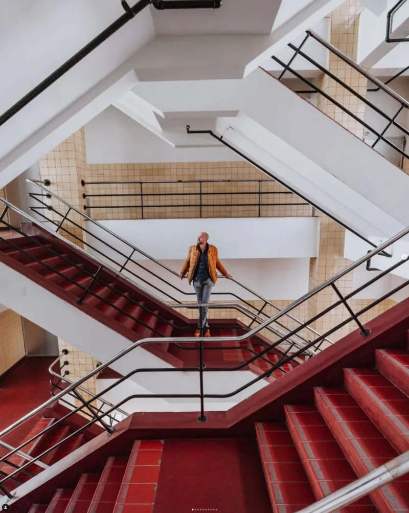 Vrouw op een rood trappenhuis, van boven met de groothoek gefotografeerd
