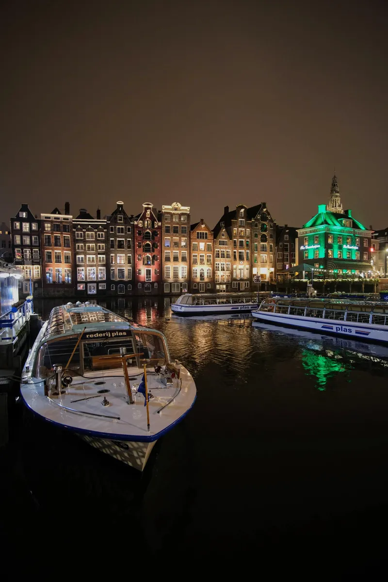 Grachtenpanden en een boot bij nacht, weerspiegeld in het water